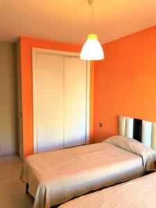 sypialnia z 2 łóżkami i pomarańczową ścianą w obiekcie Precioso apartamento frente al mar Benalbeach w mieście Benalmádena +17 zdjęć
