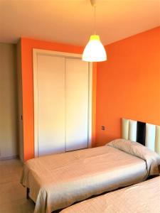 - une chambre avec 2 lits et un mur orange dans l'établissement Precioso apartamento frente al mar Benalbeach, à Benalmádena