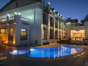 a swimming pool in front of a house at night at MİYAS LUXURY HOTEL in Kemer