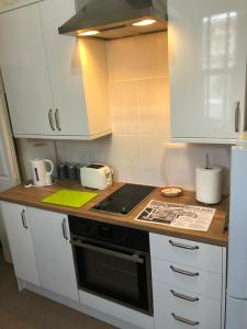 a kitchen with white cabinets and a stove top oven at Milton Lodge in Weston-super-Mare