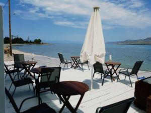 a group of tables and chairs with an umbrella and the ocean at Hotel Elafonisos in Elafonisos