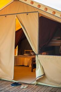 a tent with a bed in a room at Tente Lodge La Téouleyre in Saint-Julien-en-Born