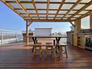 een houten terras met een tafel en twee krukken bij Magic Apartment centre mezonet in Pilsen