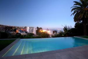 a swimming pool with a view of a city at night at Hotel Casa Higueras in Valparaíso