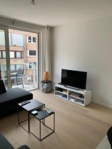een woonkamer met een bank en een tv bij Nieuwbouwappartement Lippenslaan, 2 -Slaapkamers in Knokke-Heist