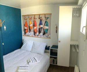 ein Schlafzimmer mit einem weißen Bett mit Surfbrettern an der Wand in der Unterkunft BELLE VUE OCEAN, 2 CHAMBRES, terrasse 30m2, parking privatif et piscine en été in Lacanau-Océan