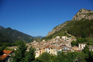 a town on a hill with mountains in the background at Hôtel Les Alizés in Puget-Théniers