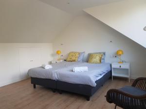 a bedroom with a large bed with two lamps and a chair at De Egel in Oostkapelle