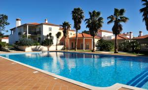 a swimming pool in front of a house with palm trees at Praia Del Rey ByThe Pools in Casal da Lagoa Seca