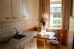 una cocina con fregadero y una mesa con un jarrón de flores en byRosi Apartments, en Parcines
