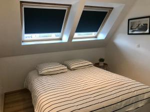 a bed with two pillows in a bedroom with two windows at Appartement Cousteau - Terras, Zeezicht, Marina in Ostend