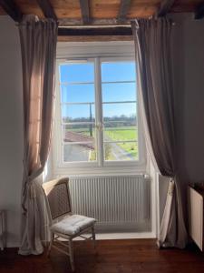 ventana con silla y vistas a un campo en L'Intemporelle, en Ozourt