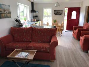 a living room with a red couch and a table at Lakeside Lookout Bantry in Cork