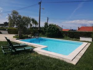 una piscina con 2 tumbonas junto a ella en Casas da Lagoa, en Santo Isidoro