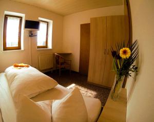 a room with a bed and a mirror and a vase of flowers at Landgasthof "Am Park" in Crottendorf