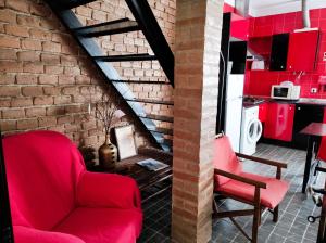 a living room with red chairs and a brick wall at Alojamento local A Giesta in Sao Sebastiao da Giesteira