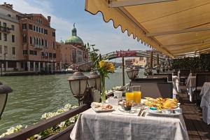 a table with food and drinks on a balcony overlooking a river at B&B Sognare A Venezia in Venice