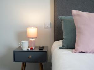 a bed with a nightstand with a lamp and a side table at Stableside at York Racecourse in York