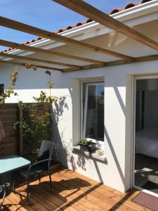 une terrasse avec une pergola, une table et des chaises dans l'établissement les aulnes de sanguinet, à Sanguinet