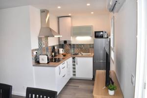 eine Küche mit einem schwarzen Kühlschrank und weißen Schränken in der Unterkunft Confort et calme au sud de Bastia in Bastia