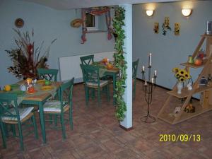 een eetkamer met groene tafels en stoelen en kaarsen bij Pension Annelie in Schullwitz