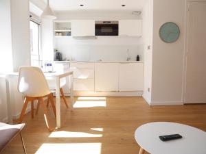 a kitchen with white cabinets and a white table at Le Chat Qui Dort in Lille