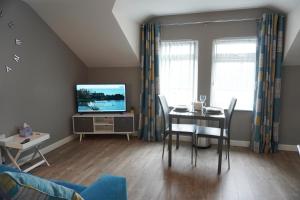 a living room with a dining table and a television at VIP Church Loft Apartment in Portadown