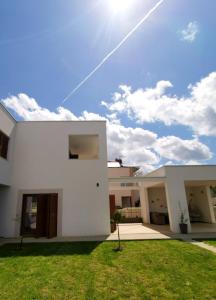 a white house with a green lawn at Apartments Leticia in Vrsi