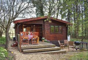 a small cabin with a table and chairs on a deck at The Cabin at The Oaks in Fordingbridge