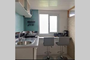 勒马兰Studio lumineux vue exceptionnelle sur la mer的厨房配有水槽和2个吧台凳