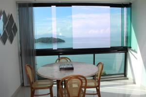 einen Tisch und Stühle in einem Zimmer mit einem großen Fenster in der Unterkunft Porto Real Resort - Apto 3 Suites Vista para o Mar in Mangaratiba