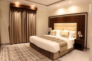a bedroom with a large bed and a large window at أمارا سويتس in Dammam