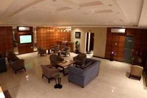 een lobby met banken en stoelen en een televisie bij أمارا سويتس in Dammam