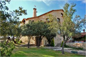an old stone house with trees in front of it at La Casona de Requijada a 6km de Pedraza con Piscina in Requijada