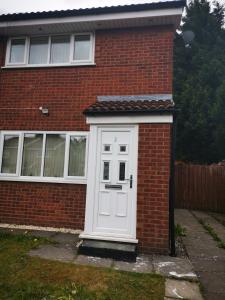 uma porta branca ao lado de uma casa de tijolos em GARDNER HOLIDAYS HOUSE em Manchester