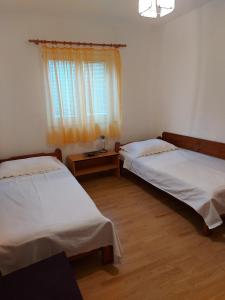 two beds in a room with a window and wooden floors at Apartmani Tatjana in Okrug Gornji