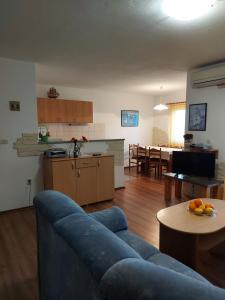 a living room with a blue couch and a kitchen at Apartmani Tatjana in Okrug Gornji