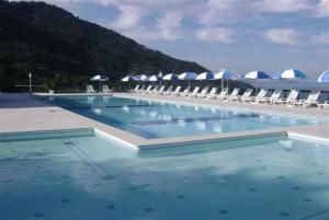 a large swimming pool with chairs and umbrellas at Porto Real Resort - Apto 3 Suites Vista para o Mar in Mangaratiba