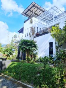 ein weißes Haus mit einem Garten davor in der Unterkunft Villa Alessa Puncak in Puncak