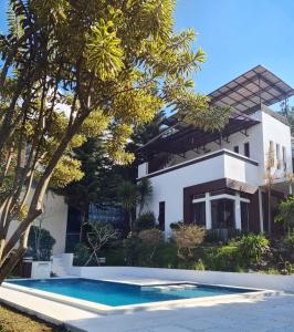 a villa with a swimming pool in front of a house at Villa Alessa Puncak in Puncak