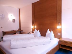 een slaapkamer met 2 bedden en witte kussens bij Hotel Schuster in Colle Isarco