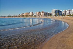 una playa con edificios y gente caminando por la playa en MoYma Playa, en Puerto Sagunto