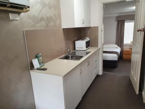 a small kitchen with a sink and a microwave at The Aston Motel Tamworth in Tamworth