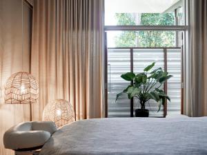 a bedroom with a bed with a plant and a window at Crystalbrook Byron in Byron Bay