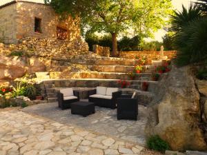 a patio with couches and chairs in front of a stone wall at Casale Ginisara in Castellammare del Golfo