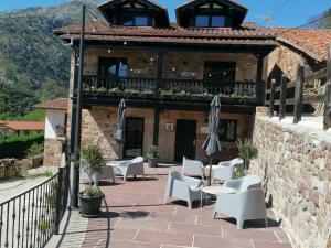 a building with chairs and umbrellas on a patio at Apartamentos Las Agüeras in Linares