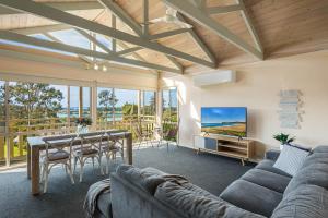 ein Wohnzimmer mit einem Sofa und einem Tisch in der Unterkunft Pelican Lake Holiday House in Merimbula