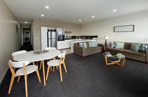 a living room with a table and chairs and a couch at Shells Apartments in Sorrento