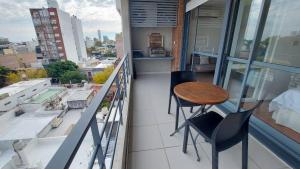 uma varanda com uma mesa e cadeiras num edifício em 1 dormitorio - zona Pichincha - Nuevo em Rosário