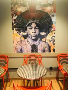 a table and chairs with a painting of a woman at Hotel Apiacas in Ribeirão Preto